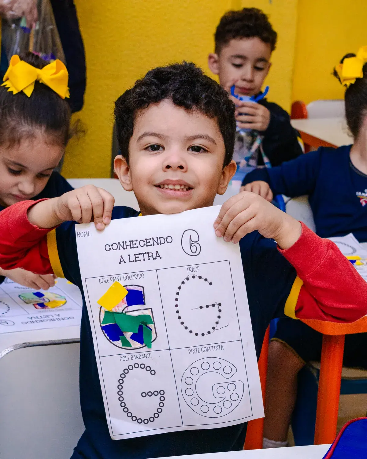 Criança da Educação Infantil mostrando a atividade de alfabetização da letra G