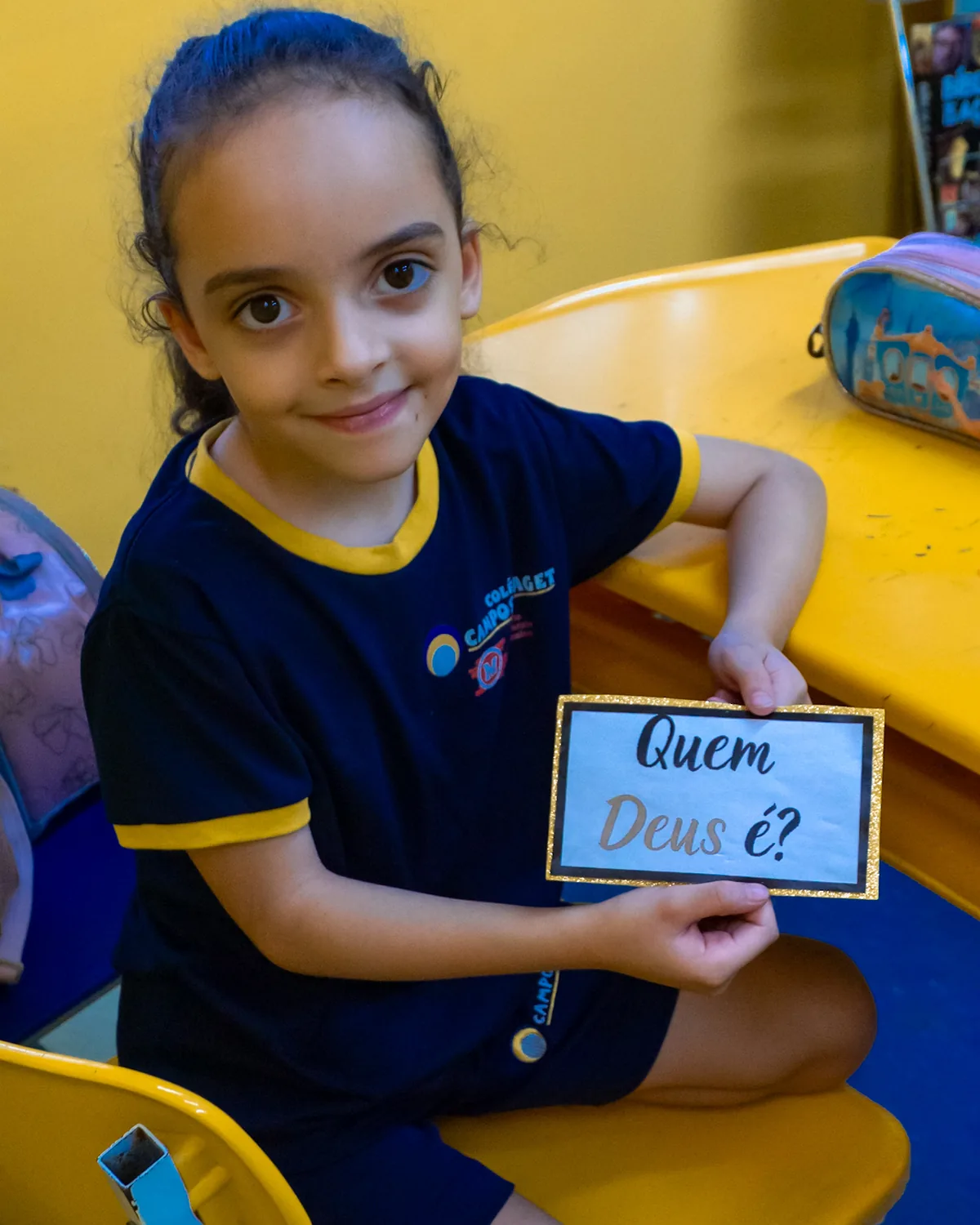 Aluna do Colégio Campos Piaget segurando um cartaz com a pergunta Quem Deus é